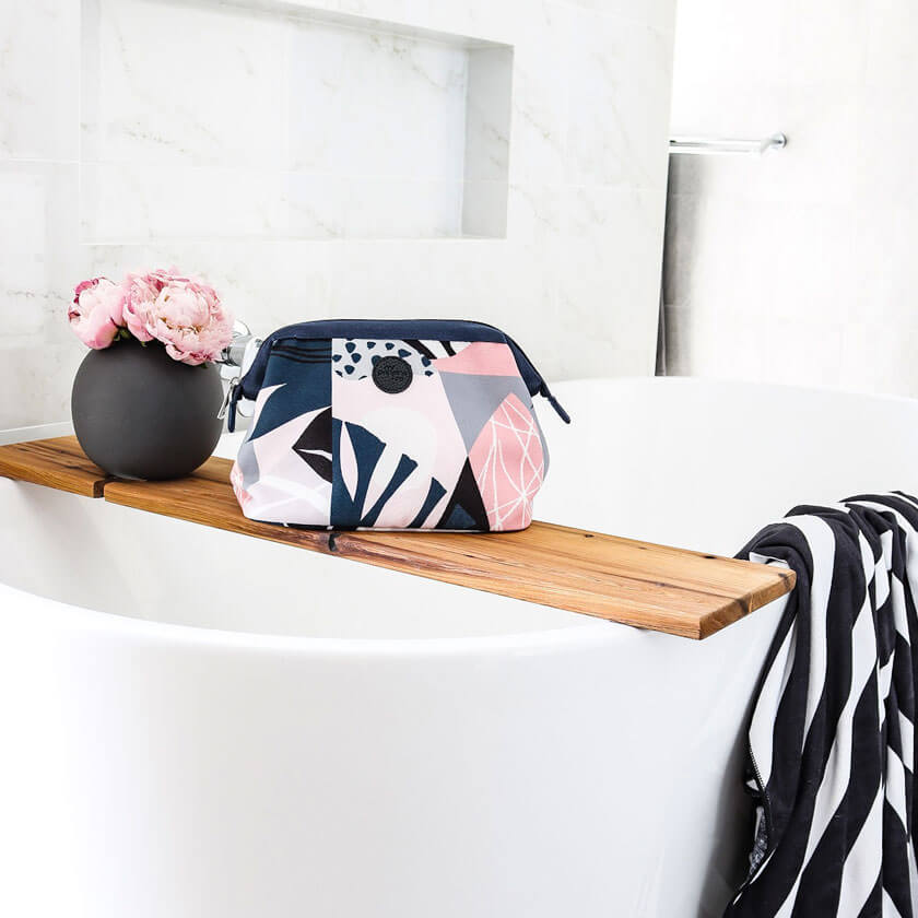 Designer toiletry bag in bathroom setting with black and white striped towel 