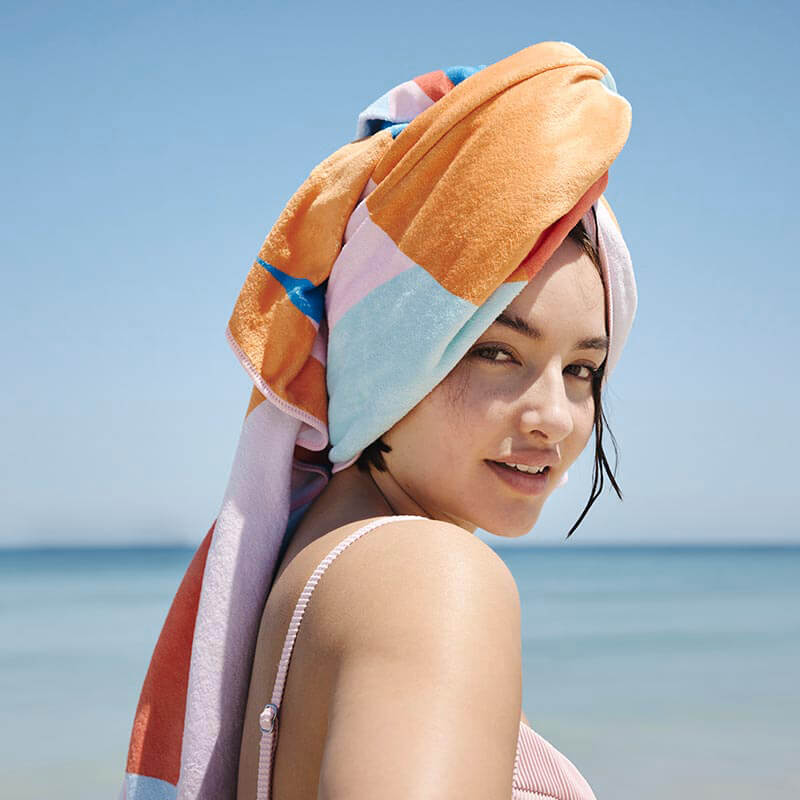 Compact sand free travel towel on woman's head
