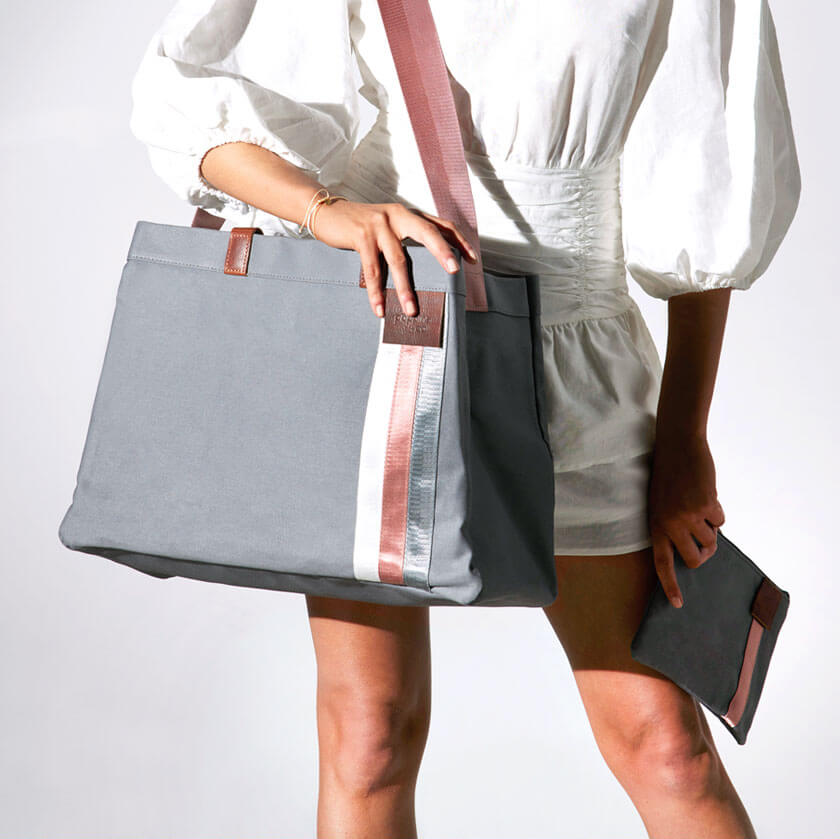 Grey everyday tote bag with pink strap over woman's shoulder 