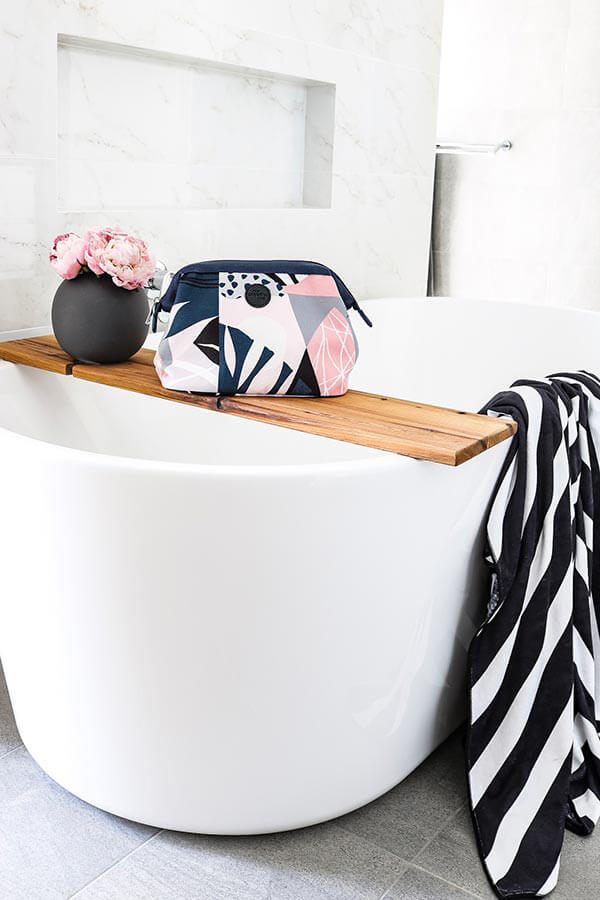toiletry bag sitting on a bath with towel draped on side