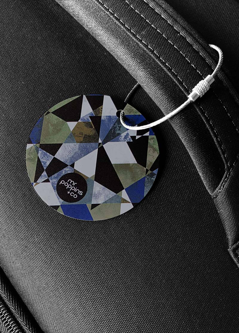 Mens metal luggage tag in geometric print on a black suitcase