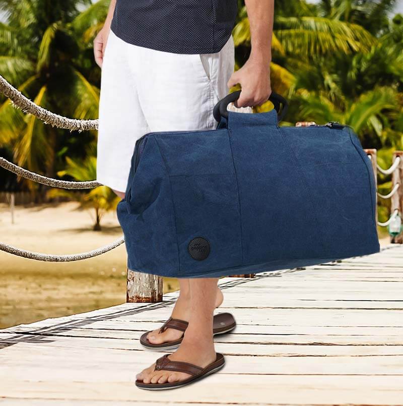 denim travel bag in man's hand on jetty
