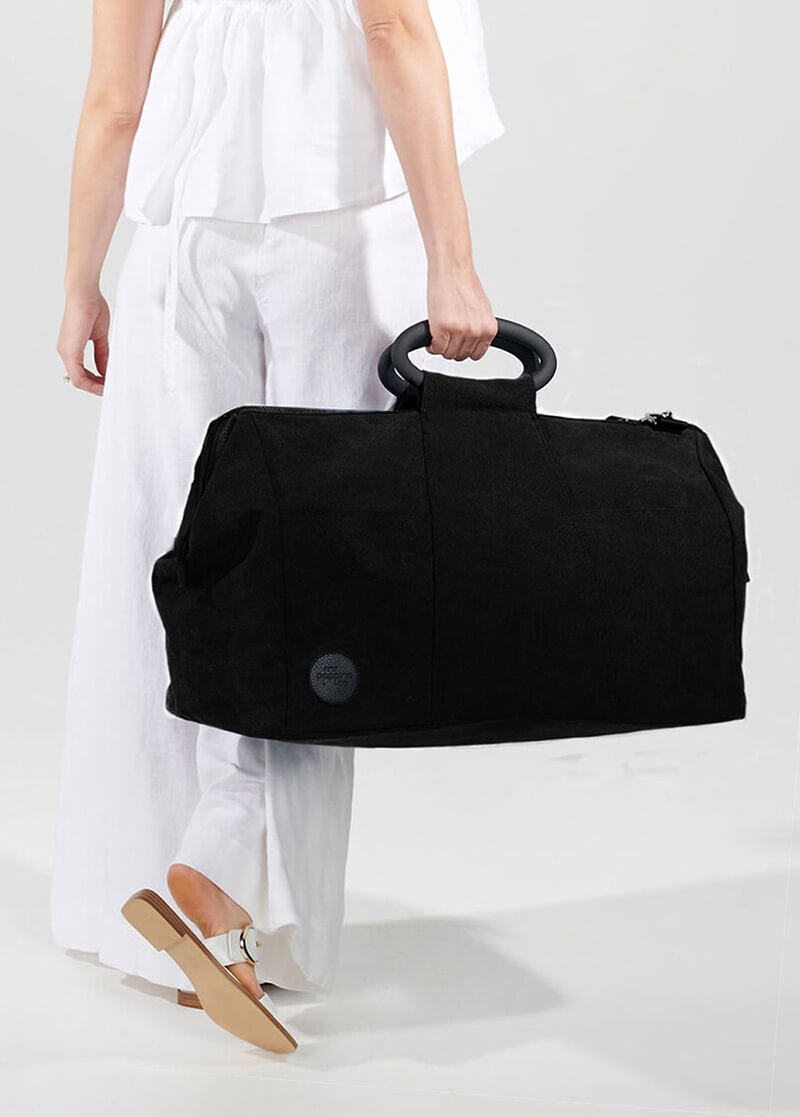 Black canvas weekend bag in woman&#39;s hand
