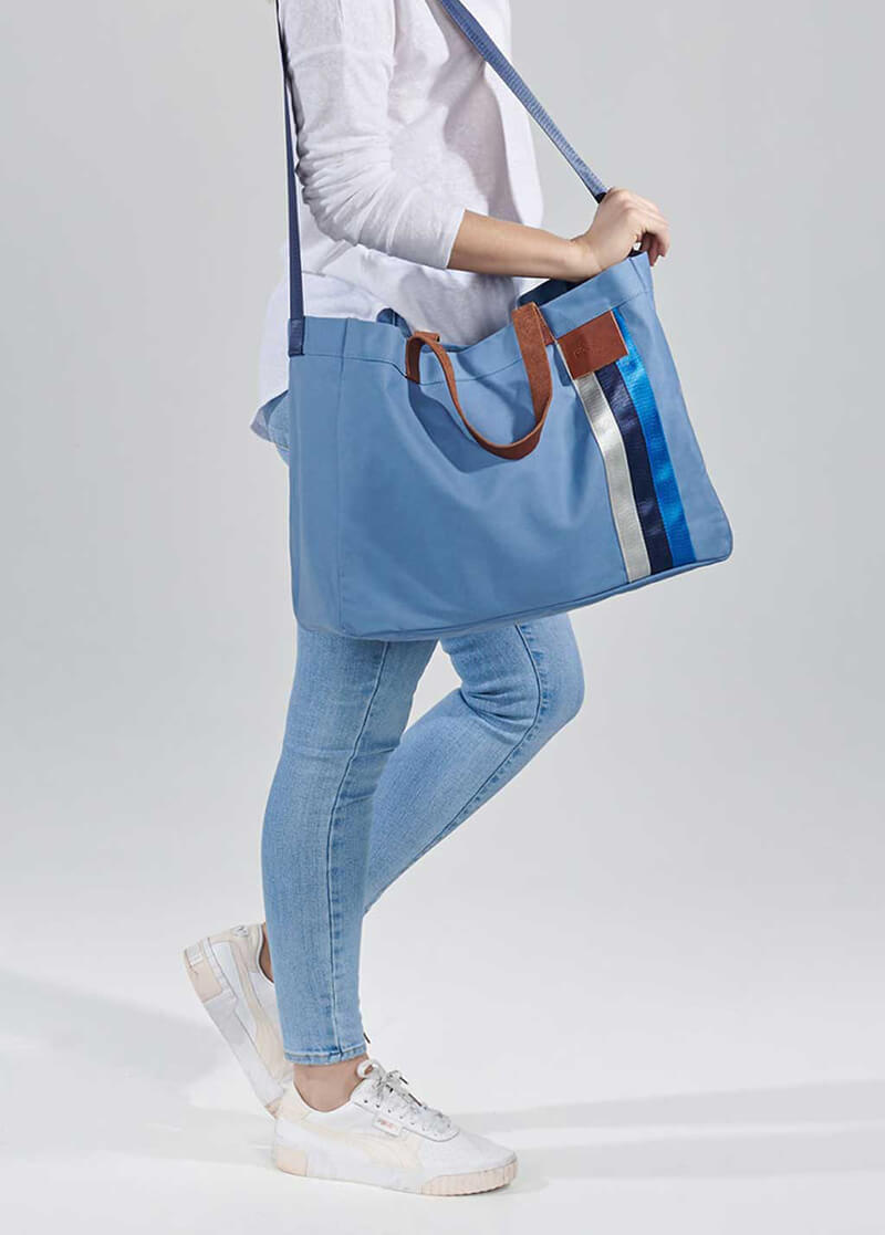 Blue everyday tote held over shoulder with the cross body strap