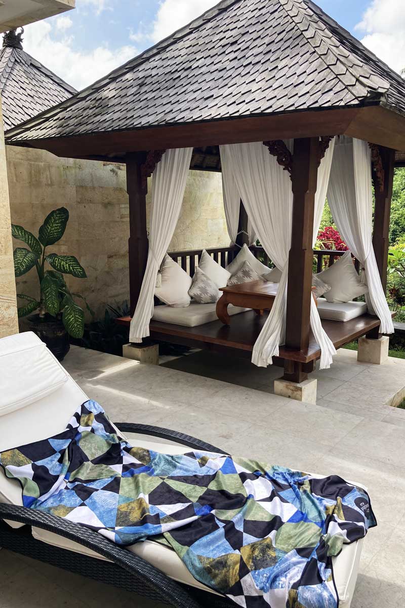 blue, khaki and black geometric towel on a deck chair infront of a bali pagola 